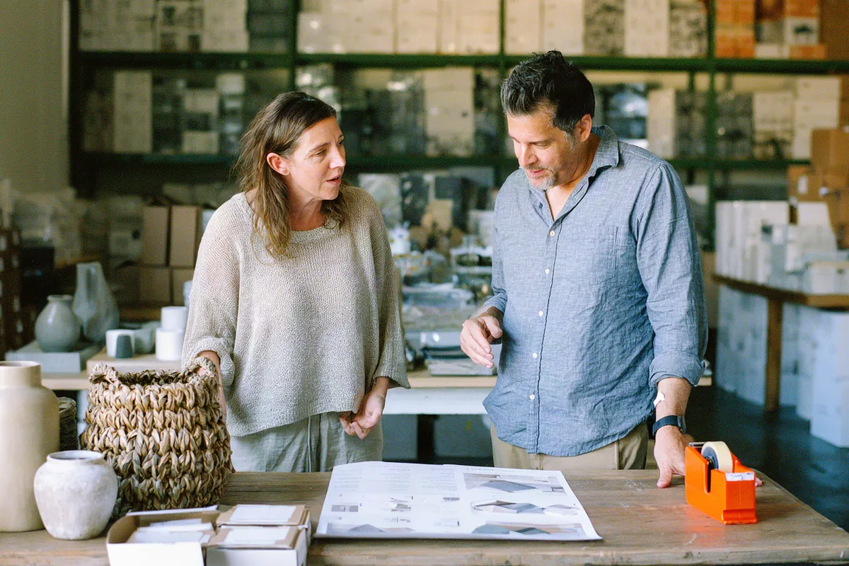 A founder and an advisor reviewing samples and a plan at a packing table