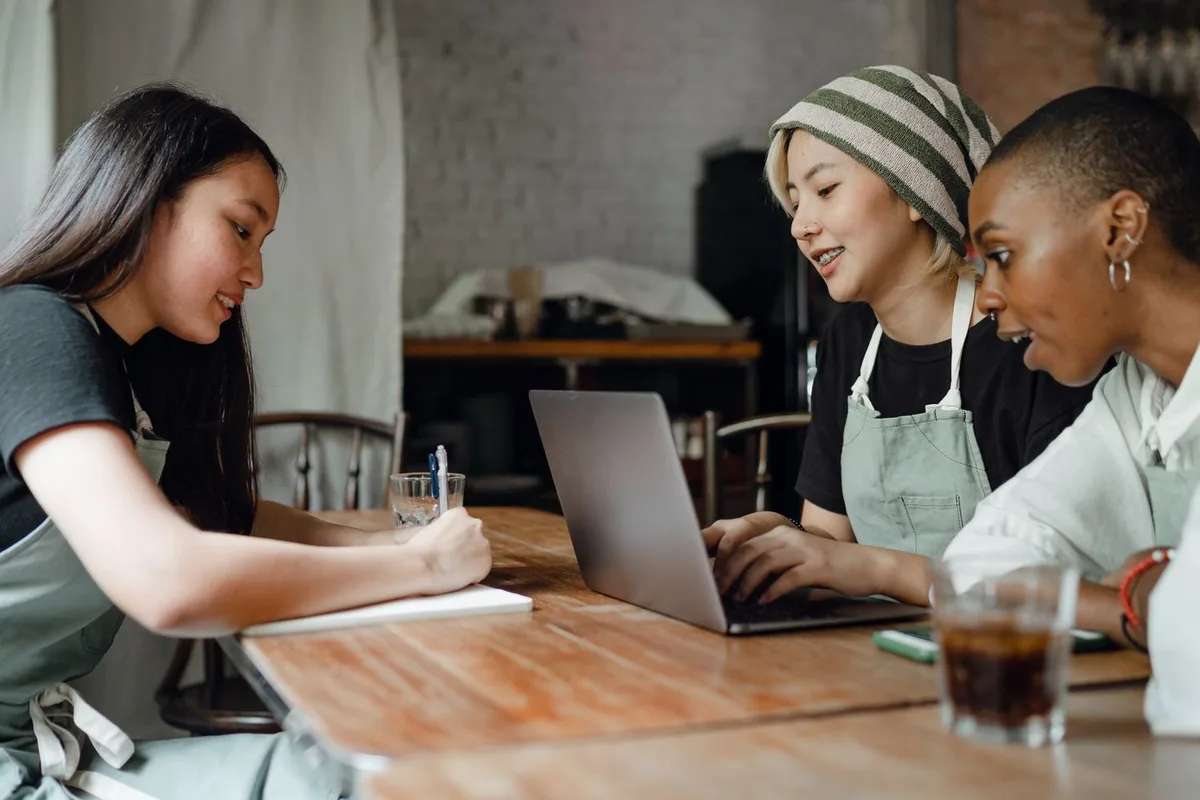 A cafe owner and two advisors working through the numbers on a laptop