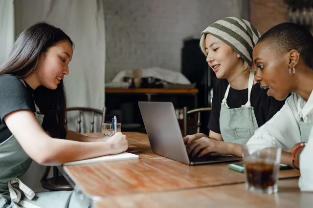 A cafe owner and two advisors working through the numbers on a laptop