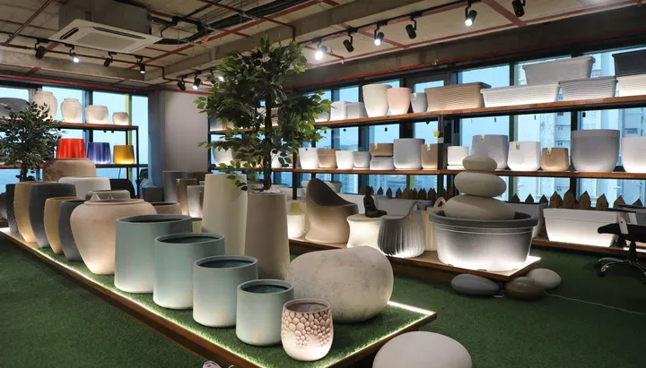 Stoneware Co. booth: glowing stoneware planters on green turf under track lights